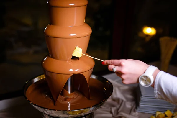 Hand with skewer takes piece of apple into chocolate  fondue — Stock Photo, Image