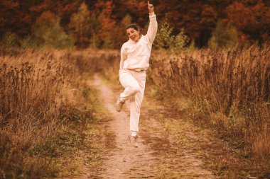 Beyaz takım elbiseli genç bir kadın spor yapıyor. Güneşli bir sonbahar günü. Yüksek kalite fotoğraf