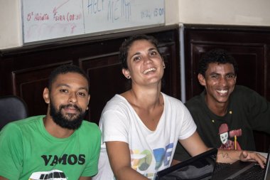 Bilgisayarın önünde mutlu bir şekilde çalışan üç kişi