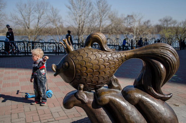 Kiev, Ukraine March 31, 2019 The boy points to the monument to the goldfish