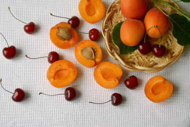 Kayısı ve vişne saman bir plaka üzerinde bir tablo olgun frui yapraklarda
