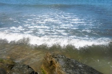 Beyaz deniz köpüğü spreyi shor yakınındaki kayalara karşı atıyor