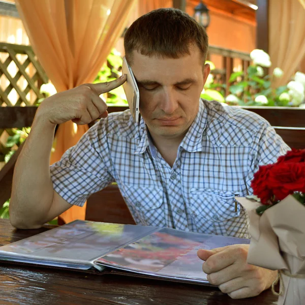 A man orders a menu and talks on the phone in a cafe during the brea