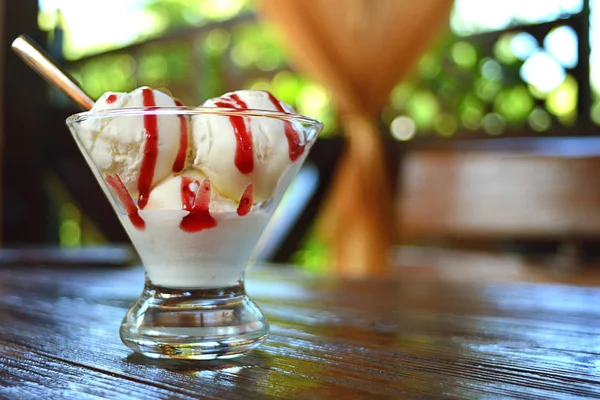 White ice cream with strawberry jam in a glass vas