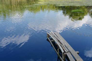 Bir köprü eski nehir üzerinde mavi gökyüzü ve bulutlar pitoresk bir yansımasıdır kirişler