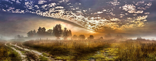 Summer village landscape with fog and a fiery sky. Russia.