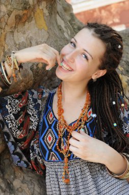 Mutlu gülümseyen indie tarzı kadın dreads ile giyinmiş boho stil süs elbise açık poz içinde
