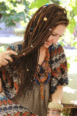 Dreadlocks, sevimli gülümseyen hippi indie tarzı kadın giyinmiş boho stil süs elbise açık poz içinde