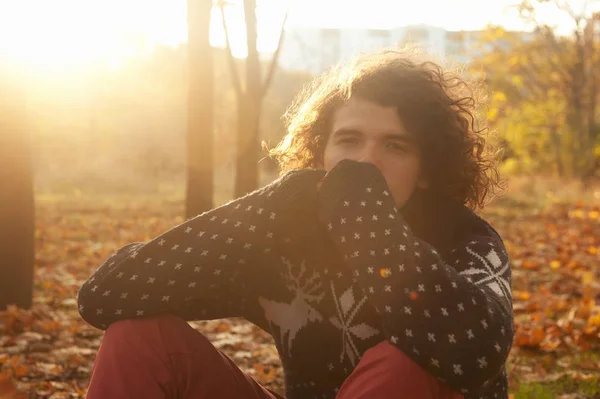 年轻的郁闷男子身着针织毛衣坐在秋季叶子在公园 秋季抑郁症的概念 — 图库照片