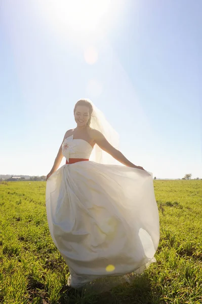 Junge Braut im langen weißen Kleid auf der grünen Wiese — Stockfoto