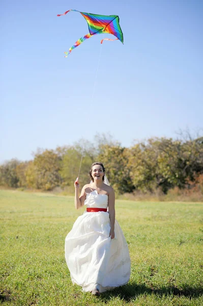 Невеста идет по полю с воздушным змеем — стоковое фото