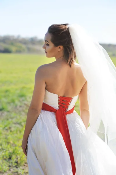 Young bride outdoor portrait in white dress against green field — Stock Photo, Image