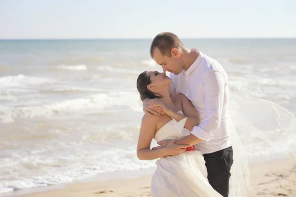 Junges erwachsenes Hochzeitspaar küsst sich am Meer — Stockfoto