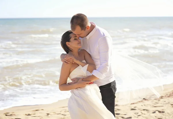 La novia y el novio se apoyan uno contra el otro en un mar — Foto de Stock