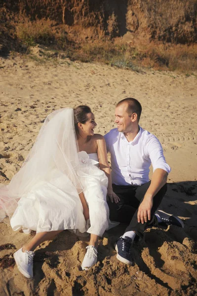 Unga brudparet sitter på en sand på stranden — Stockfoto