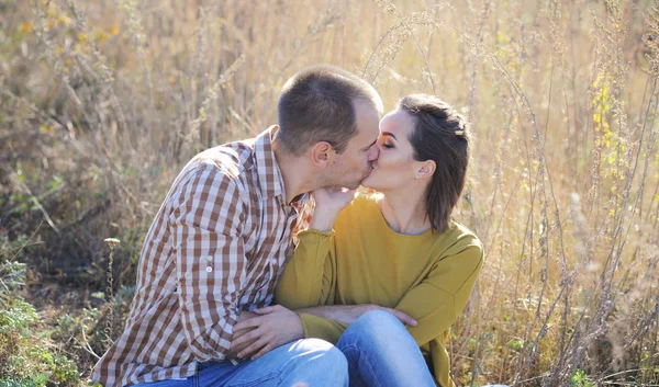 Giovane adulto baciare amore coppia, hanno un resto all'aperto, seduto su erba — Foto Stock