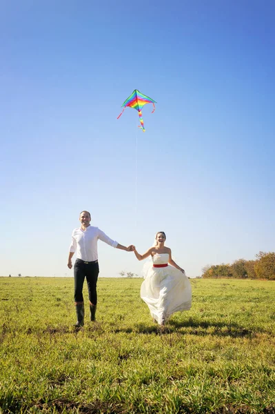 Bastante joven pareja de boda adulto caminando en el campo con cometa — Foto de Stock