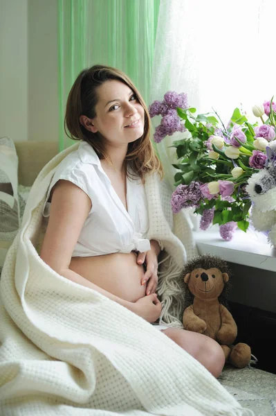 Mooie zwangere vrouw portret zittend in de buurt venster — Stockfoto