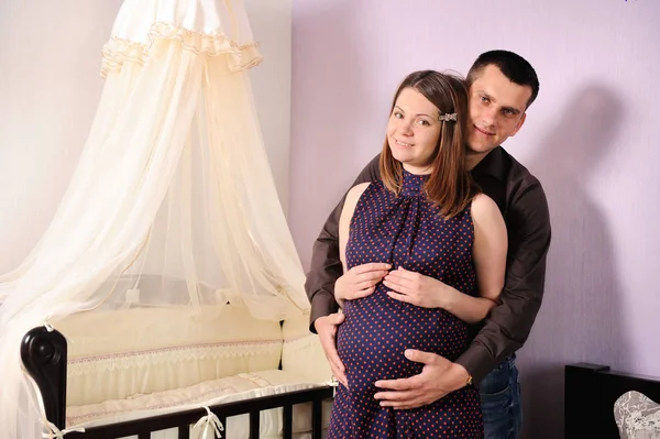 Happy couple future parents portrait, standing near a cot and lo — Stock Photo, Image