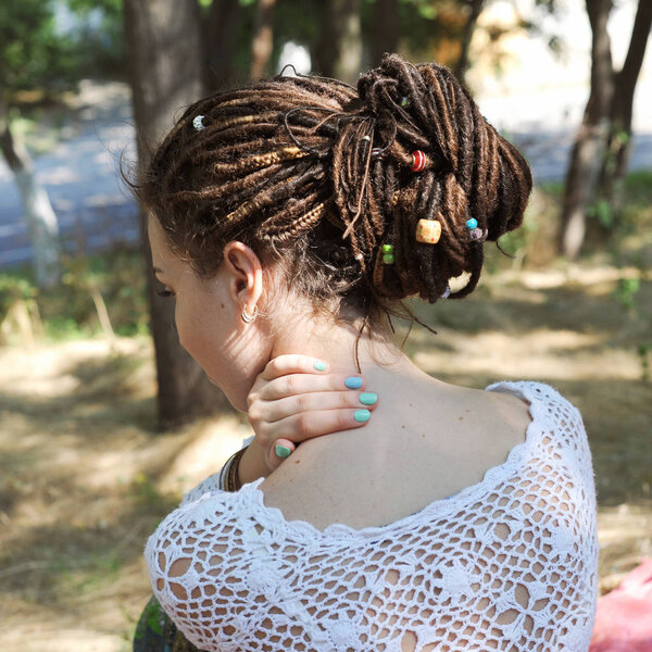 Woman with dreadlocks hairstyle gathered in a ponytail, decorated assorted beads