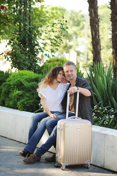 Felices turistas amor pareja hablando al aire libre, sentado en un banco en el parque de la ciudad — Foto de Stock