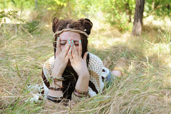 Fröhliche Frau im Indie-Stil mit Dreadlocks-Frisur, hat Spaß dabei, ihr Gesicht mit einer Hand zu schließen — Stockfoto