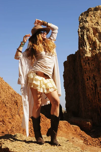 Foto de moda al aire libre de la joven mujer feliz en el sombrero, standigg contra las rocas, manos arriba — Foto de Stock