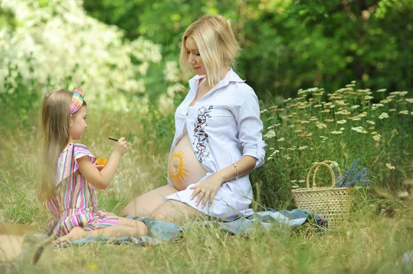 Niña dibujar un sol en su estómago madre embarazada —  Fotos de Stock