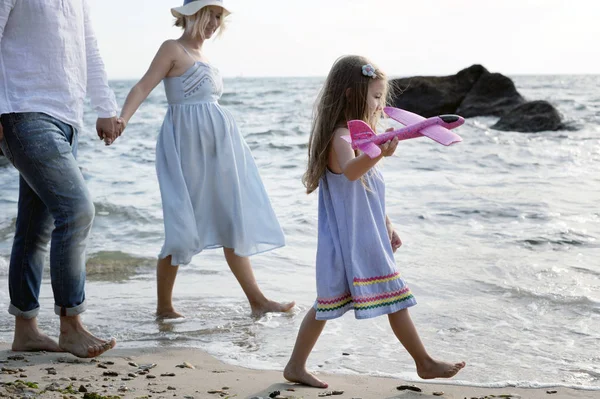 Счастливая семья будущих родителей с прогулкой у моря — стоковое фото