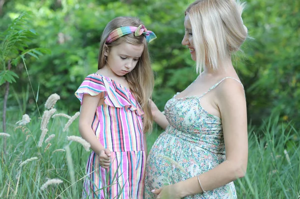 Mulher grávida feliz e sua filha no parque de verão — Fotografia de Stock