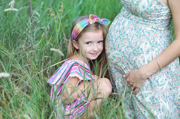 Szczęśliwa Kobieta w ciąży i jej córka w parku letnim — Zdjęcie stockowe