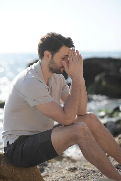 Deprimerad ledsen ung man sitter på en havsstrand — Stockfoto