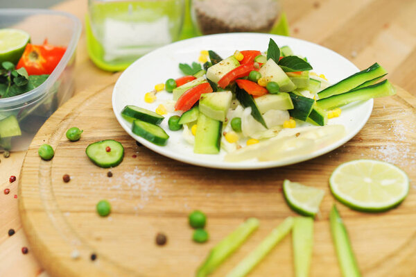Bowl of salad with vegetables and greens on wooden table in outdoor cafe
