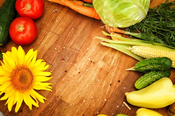 Marco vegetal de verano hecho con girasoles y verduras frescas surtidas en tablero de madera vintage — Foto de Stock