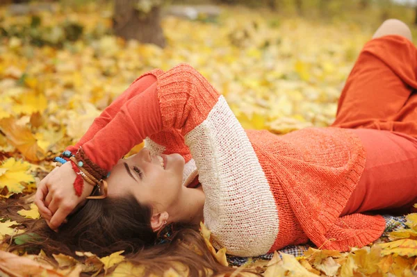 Retrato de menina descansando feliz, deitado em folhas de bordo de outono no parque, olhos fechados, vestido com suéter de moda — Fotografia de Stock