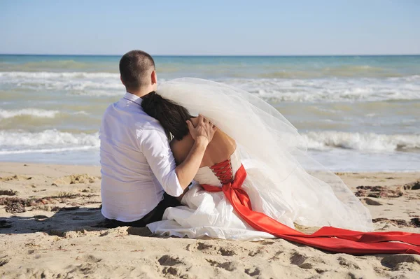 Söt bröllopspar sitter på en sand, ryggen, inget ansikte — Stockfoto