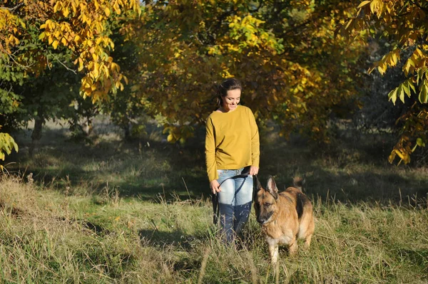 Portrait de jeune femme avec leur chien de berger allemand dans le parc d'automne — Photo