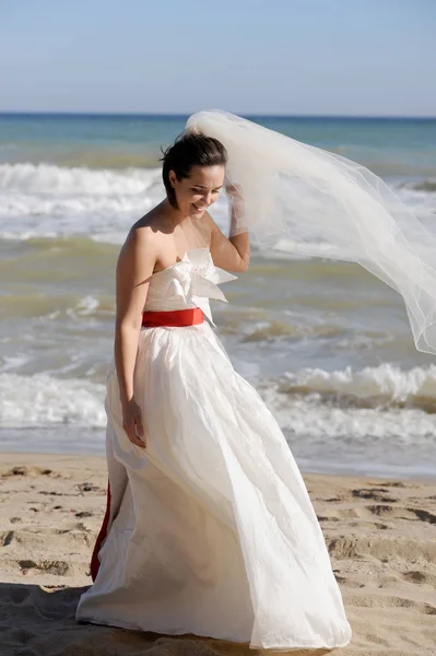 Pretty young bride walking on a sea beach — Stock Photo, Image