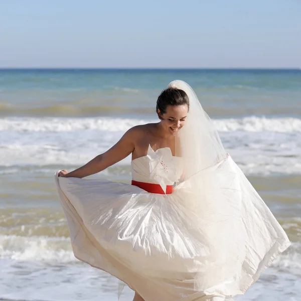 Hübsche junge Braut zu Fuß auf einem Strand — kostenloses Stockfoto