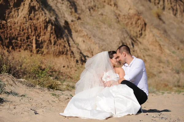 Young wedding couple sitting on a sand on the beach — Stock Photo, Image