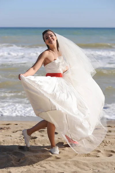 Happy bride walking on a sea beach — Stock Photo, Image