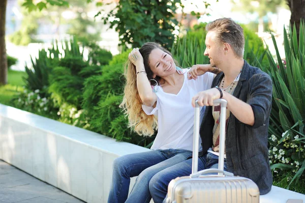 Felices turistas amor pareja hablando al aire libre, sentado en un banco en el parque de la ciudad — Foto de Stock