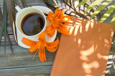 Sabah kahveyle, defterle, açık havada palmiye gölgeli yaz fotoğrafıyla, düz bir şekilde yatarak.