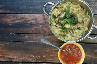 Ahşap bir masada makarna ve domates soslu Akdeniz yemeği.