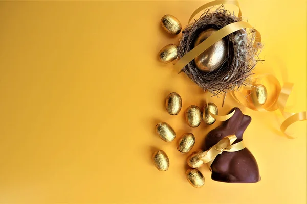 Huevos de Pascua de chocolate dorado y conejito de chocolate en una ba amarilla —  Fotos de Stock