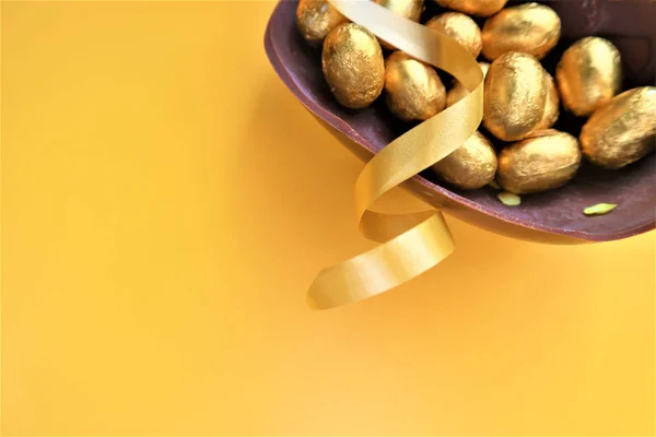 Huevos de Pascua de chocolate dorado sobre fondo amarillo —  Fotos de Stock