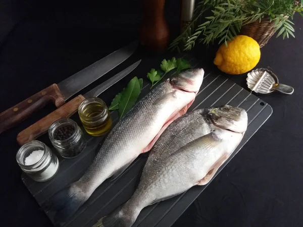 Peixe fresco com limão e temperos em preto — Fotografia de Stock