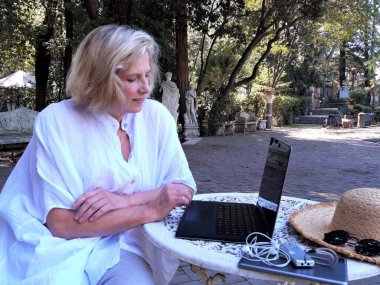 Neşeli olgun kadın dizüstü bilgisayar kullanarak dinlenirken