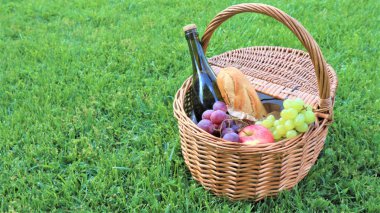 Beyaz ve siyah üzümlü hasır piknik sepeti ve şarap.