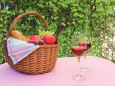 Pembe peçete piknik sepeti ve iki kadeh şarap.